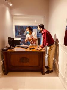un hombre y una mujer de pie en un escritorio con una computadora en Hotel Jukaso Inn Down Town, en Nueva Delhi