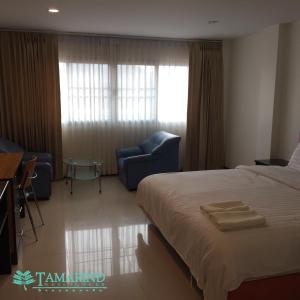 Habitación de hotel con cama, sillas y ventana en Tamarind Residences Khonkaen บ้านแทมมารีน, en Khon Kaen