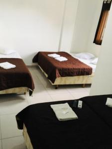 two beds in a hotel room with towels on a table at Hotel Santos Reis in Aparecida