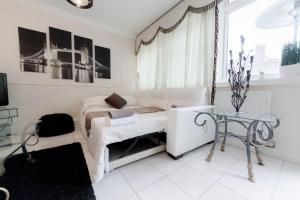 ein weißes Wohnzimmer mit einem Sofa und einem Tisch in der Unterkunft Juzz Holiday Lets in London