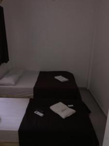 two beds in a small room with towels on them at Hotel Santos Reis in Aparecida