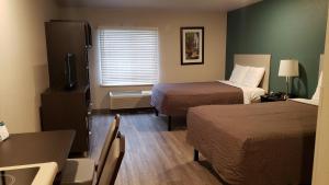 Habitación de hotel con 2 camas, mesa y sillas en WoodSpring Suites Kansas City Mission, en Merriam