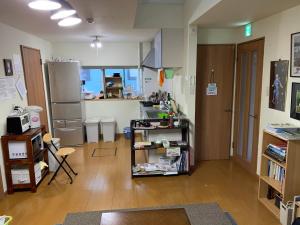 a room with a kitchen with a counter and a refrigerator at Guesthouse TOMAYA in Nemuro