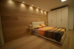 1 dormitorio con 1 cama y pared de madera en Appartamento Margherita - Bellagio Wild Flowers en Oliveto Lario
