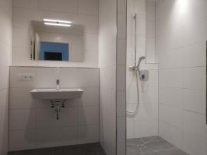 a white bathroom with a sink and a shower at Apartment "SUN" in Friedrichshafen +16 photos