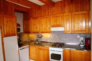 a kitchen with wooden cabinets and a white stove top oven at Eanta SUNNY & MOUNTAIN chalet 10 pers by Alpvision Résidences in Veysonnaz