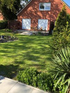 un patio con una casa con césped en Ferienhaus Pilsum, en Krummhörn