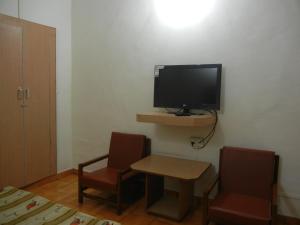 a room with a television and two chairs and a table at Hotel Grand Barrack in Khandwa