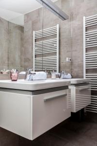 a white bathroom with two sinks and a mirror at Roses apartment in Brno