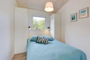 a bedroom with a bed with blue sheets and a window at Eksklusiv feriebolig med panoramaudsigt in Munkebo