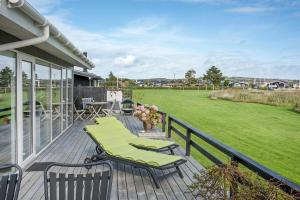 a deck with chairs and a field of grass at Eksklusiv feriebolig med panoramaudsigt in Munkebo
