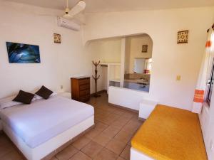 a bedroom with a white bed and a bathroom at Villa Casalet in Puerto Escondido