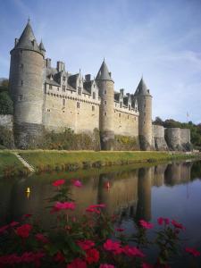 a castle with pink flowers in front of a body of water at Central Brittany B and B in Rohan