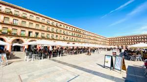 a large building with tables and chairs and umbrellas at Hostel Plaza Mayor Corredera in Córdoba +33 photos