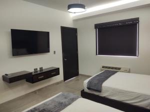 a bedroom with two beds and a flat screen tv at SAND MAR HOTEL in Puerto Peñasco