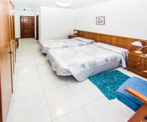 a bedroom with two beds and a blue rug at Hotel Restaurante Xaneiro in Melide