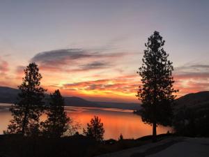 a sunset over a lake with trees in the foreground at Lakeside Lodge and Suites in Chelan