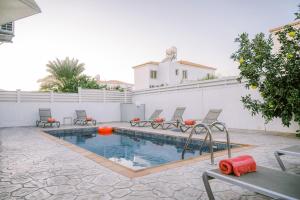 a swimming pool with chairs and a table and a building at Villa Costa Cornelia Homes in Ayia Napa
