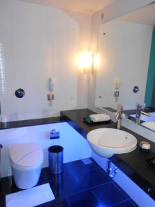 een badkamer met een wastafel, een toilet en een spiegel bij Citrine in Bangalore
