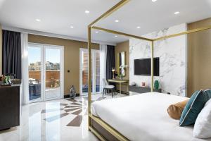a bedroom with a bed and a desk and a television at Lure Hotel & Spa - Adults Only in Mellieħa