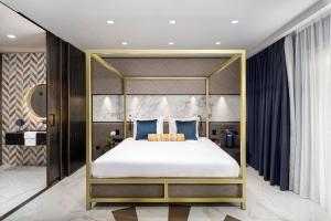 a bedroom with a canopy bed with blue pillows at Lure Hotel & Spa - Adults Only in Mellieħa