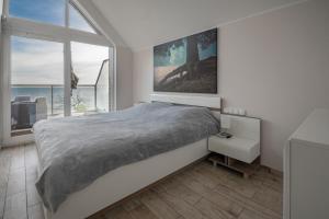 a bedroom with a large bed and a large window at Apartament na Klifowej in Mechelinki