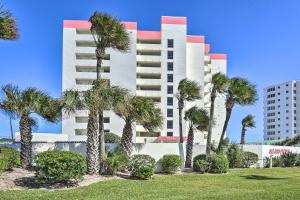 a tall building with palm trees in front of it at Oceanfront Retreat with Pool Steps From Ormond Beach in Ormond Beach