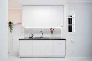 eine Küche mit weißen Schränken und einem Waschbecken in der Unterkunft Crystal Apartment Katowice IV in Kattowitz