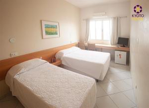 um quarto de hotel com duas camas e uma secretária em Kyoto Hotel em São Paulo