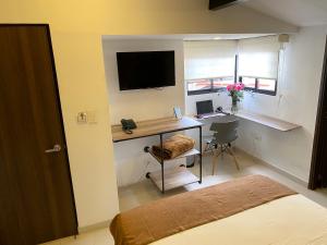 a bedroom with a desk with a computer and a monitor at Rivière Boutique Hotel in Medellín
