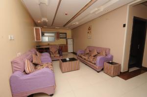 sala de estar con sofás morados y cocina en مون تري للشقق المخدومة فرع الرياض, en Riad