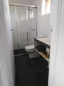 a bathroom with a toilet and a glass shower at Altona Motel in Uralla