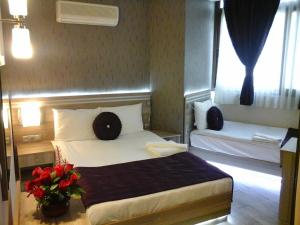 a hotel room with a bed and a vase of flowers at Olimpiyat Hotel Izmir in İzmir