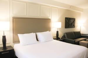 Habitación de hotel con cama blanca y silla en Best Western Plus Winkler en Winkler