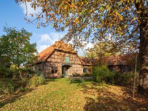 an old stone building with a tree in front of it at Historic half timbered Farm in Hohnebostel near Watersports in Langlingen