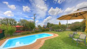 una piscina en un patio con sombrilla en Alluna Motel, en Armidale