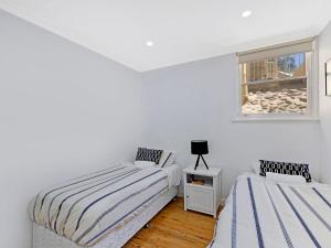 2 łóżka w białym pokoju z oknem w obiekcie Golden Sands 1 - Absolute Beachfront w mieście Blue Bay 