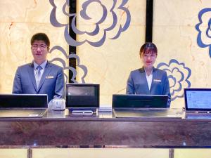 zwei Personen sitzen an einem Tisch mit Laptops in der Unterkunft Hangzhou Tower Hotel in Hangzhou