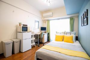 a bedroom with a bed with yellow pillows and a desk at Wings Hakata in Fukuoka