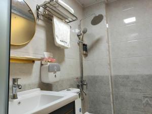 ein Bad mit einer Dusche, einem Waschbecken und einem Spiegel in der Unterkunft Jieyang Yunduo Hotel (Chaoshan Airport) in Jieyang