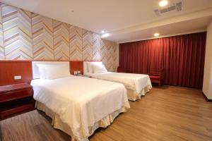 um quarto de hotel com duas camas e uma cortina vermelha em Chuan Fu Hotel em Fengyuan