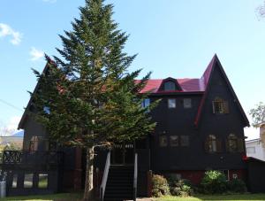 Un árbol de Navidad delante de una casa negra en Pension Fullnote en Niseko