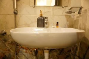 un lavandino bianco in un bagno con specchio di THE CHIRAAG INN a Chennai