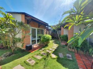 a house with a garden in front of it at Tuong Vy Boutique Hotel Mui Ne in Mui Ne