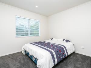 um quarto branco com uma cama e uma janela em Millies Place - Mangawhai Holiday Home em Mangawhai