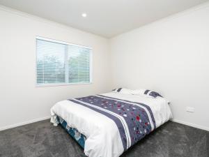 a white bedroom with a bed and a window at Millies Place - Mangawhai Holiday Home in Mangawhai