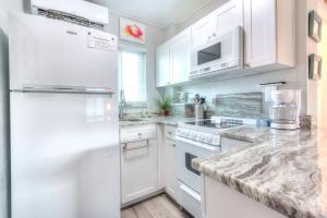 uma cozinha branca com electrodomésticos brancos e armários brancos em Tropic Terrace #49 - Beachfront Rental condo em St. Pete Beach