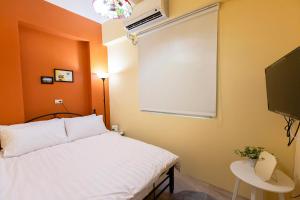 Schlafzimmer mit einem weißen Bett und einem Flachbild-TV in der Unterkunft Lin Cuo Bian Homestay in Zhushan