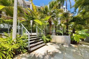 Un escalier mène à un bâtiment avec des palmiers. dans l'établissement Naousa II Apartment 5, Little Cove, à Noosa Heads