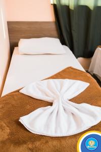 a bed with a white blanket on top of it at Don Charleaux Hotel in Aparecida